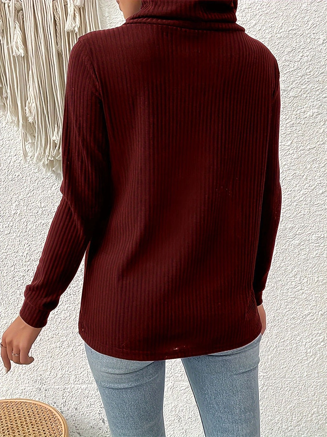 Burgundy ribbed turtleneck sweater with asymmetric button detail.