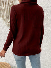 Burgundy ribbed turtleneck sweater with asymmetric button detail.