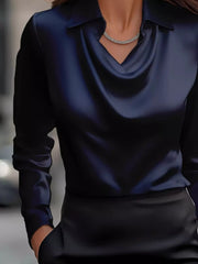 Dark blue satin cowl neck long-sleeve blouse with a collar and a necklace.