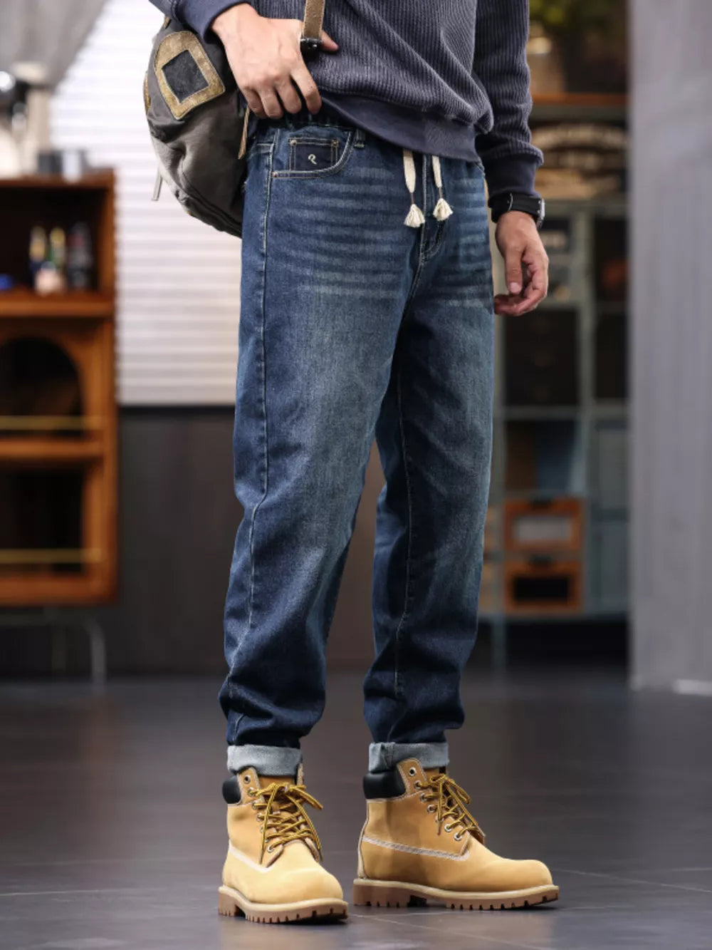 Men's relaxed fit drawstring jeans in blue denim with a drawstring waist and cuffed hems.