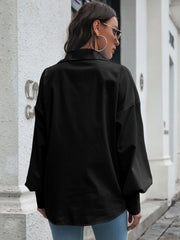 Black oversized poplin blouse with blouson sleeves and buttoned cuffs.