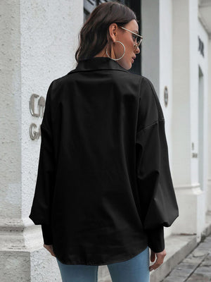 Black oversized poplin blouse with blouson sleeves and buttoned cuffs.