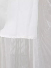 White maxi dress hem detail with sheer overlay and subtle vertical pleating.