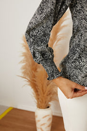 Black serpentine print blouse with gathered long sleeves and elastic cuffs.