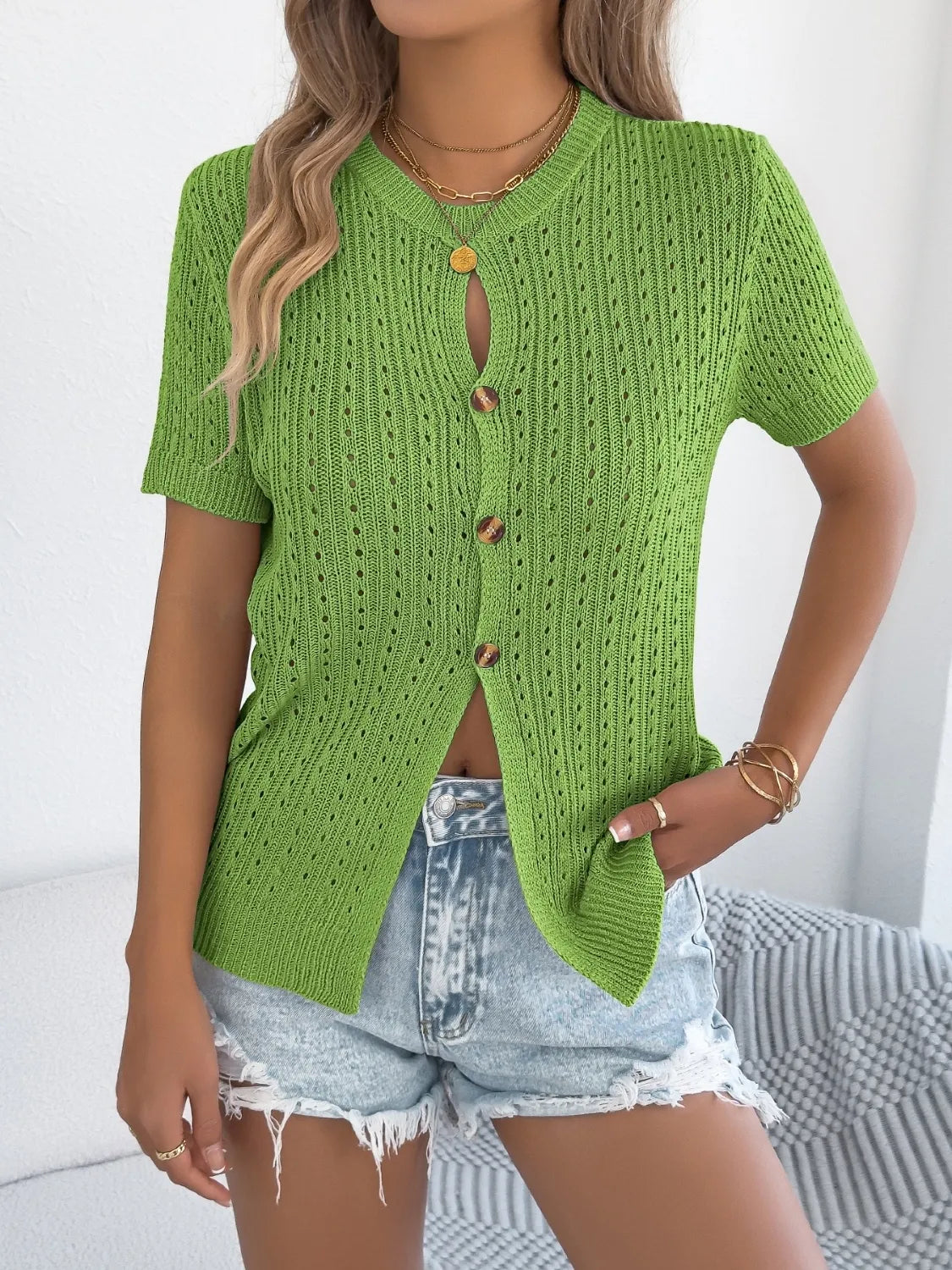 Green knit button-up cardigan with short sleeves and a textured open knit.