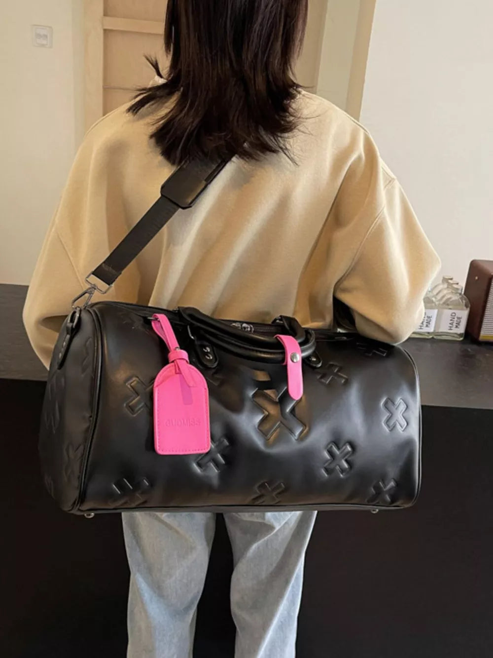 Black embossed cross detail luxury duffel bag with pink tag
