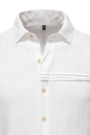 White linen shirt with buttoned collar, pleated pocket detail, and natural buttons.