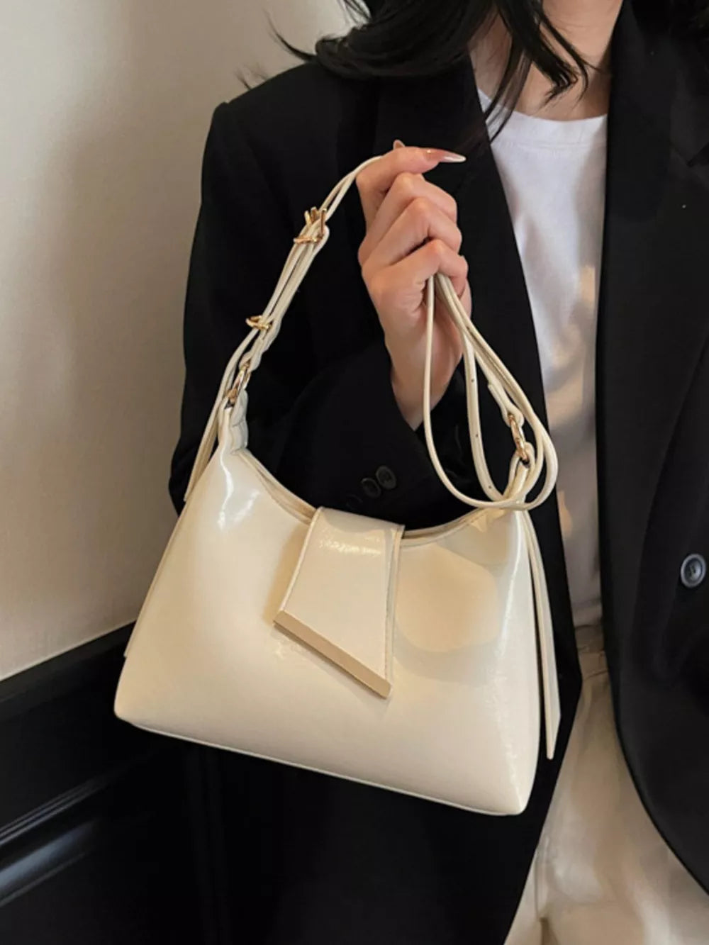 Adjustable strap crossbody bag in beige with gold hardware detail.