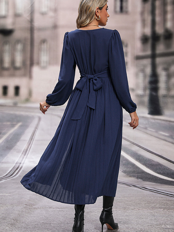 Dark blue maxi dress with long sleeves, a tie waist, and pleated skirt.