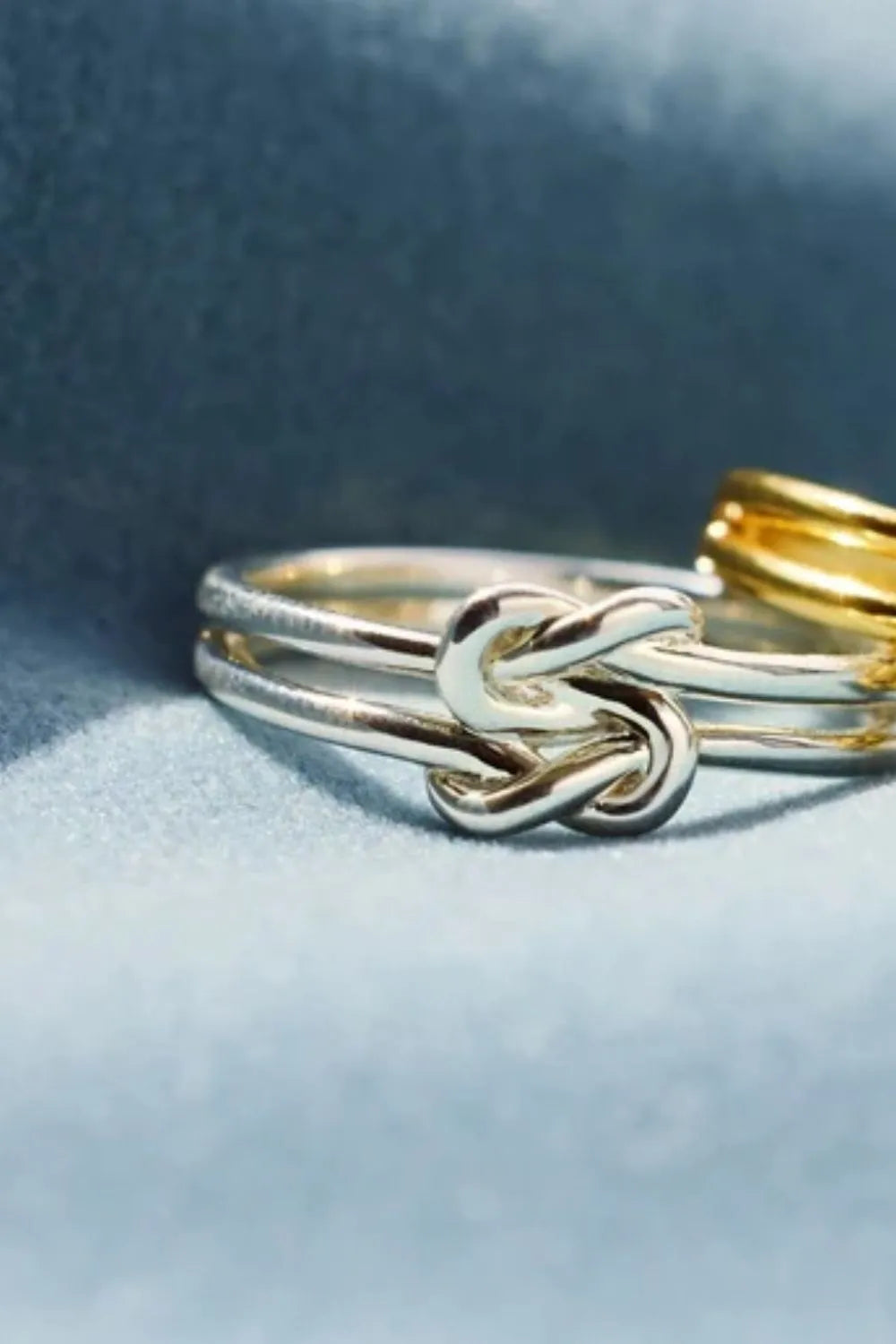 Double band knot ring in silver with a gold ring in the background