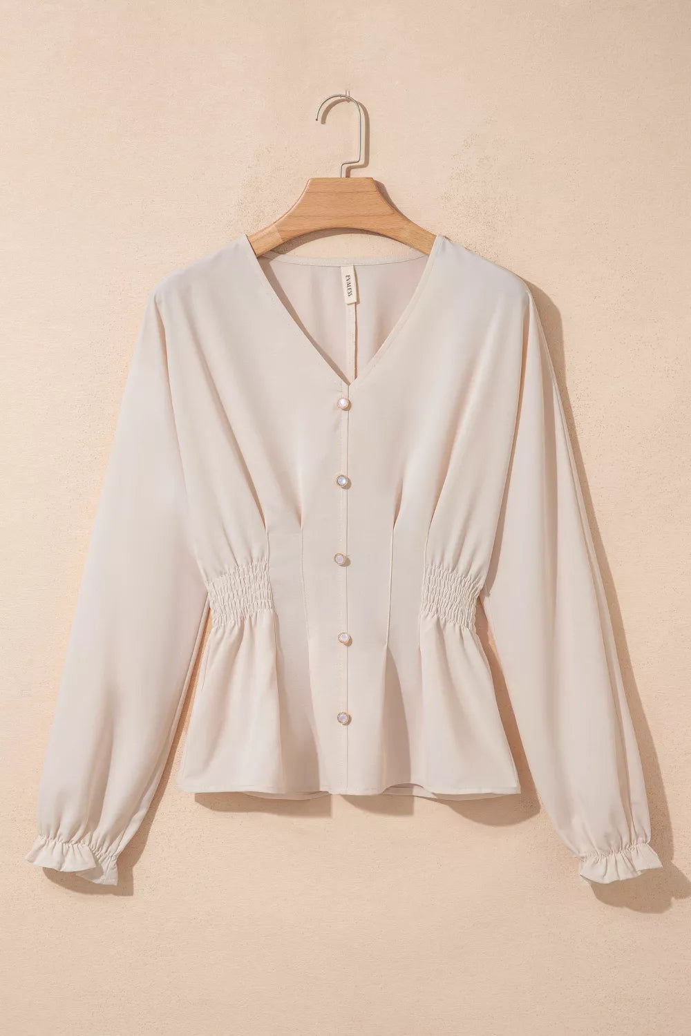 Elegant V-neck polyester blouse with smocked waist and button front in cream.