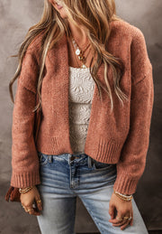 Open-front cropped knit cardigan in burnt coral acrylic with ribbed cuffs and hem.