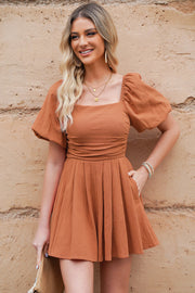 Ochre square neck puff sleeve romper with cinched waist and pleated skirt.