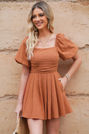 Ochre square neck puff sleeve romper with cinched waist and pleated skirt.
