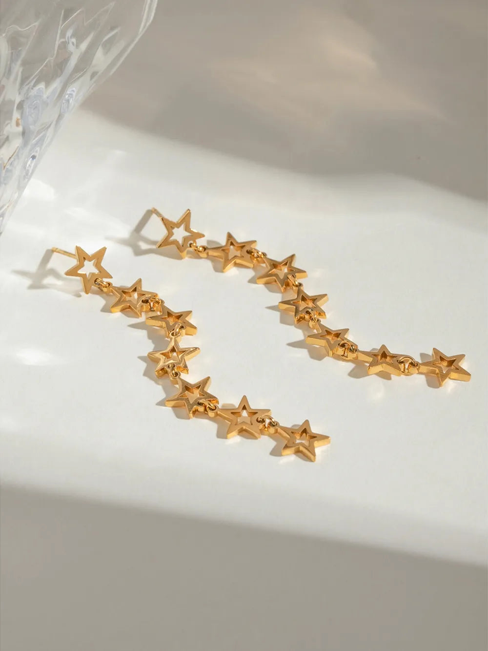 Gold celestial star drop earrings with a cascading design.