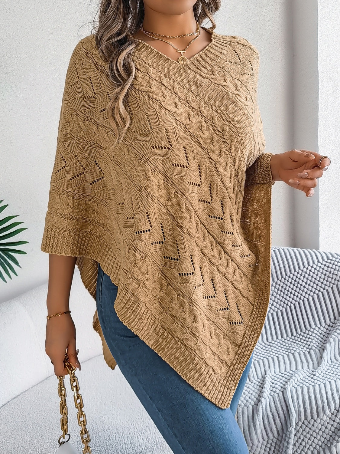 Camel cable knit poncho with chevron detail and v-neck, styled with jeans.