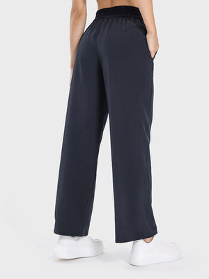Charcoal relaxed drape drawstring palazzo pants with pockets, styled with white sneakers.