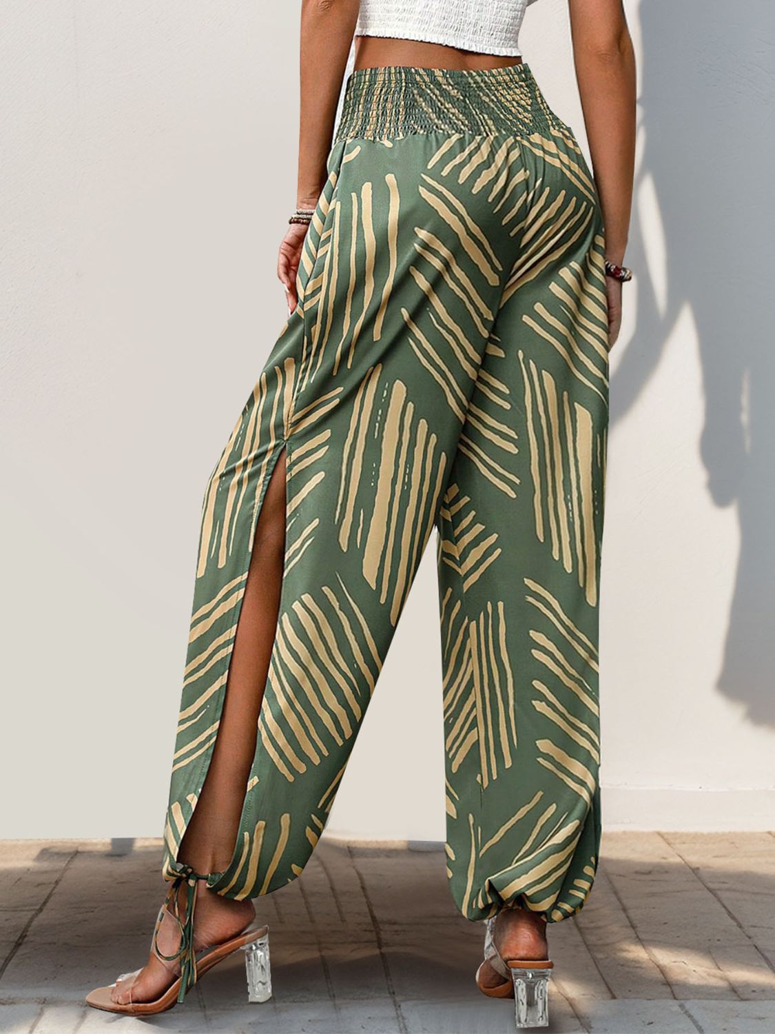 Moss green palazzo trousers with abstract print, smocked waist, and high slit legs.