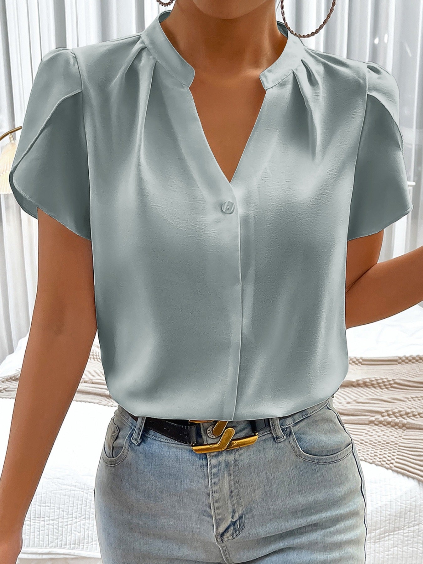 Light blue satin blouse with notched neckline, petal sleeves, and button detail.