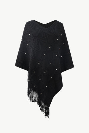 Black knit poncho with geometric pattern, pearl embellishments, and fringe detail.