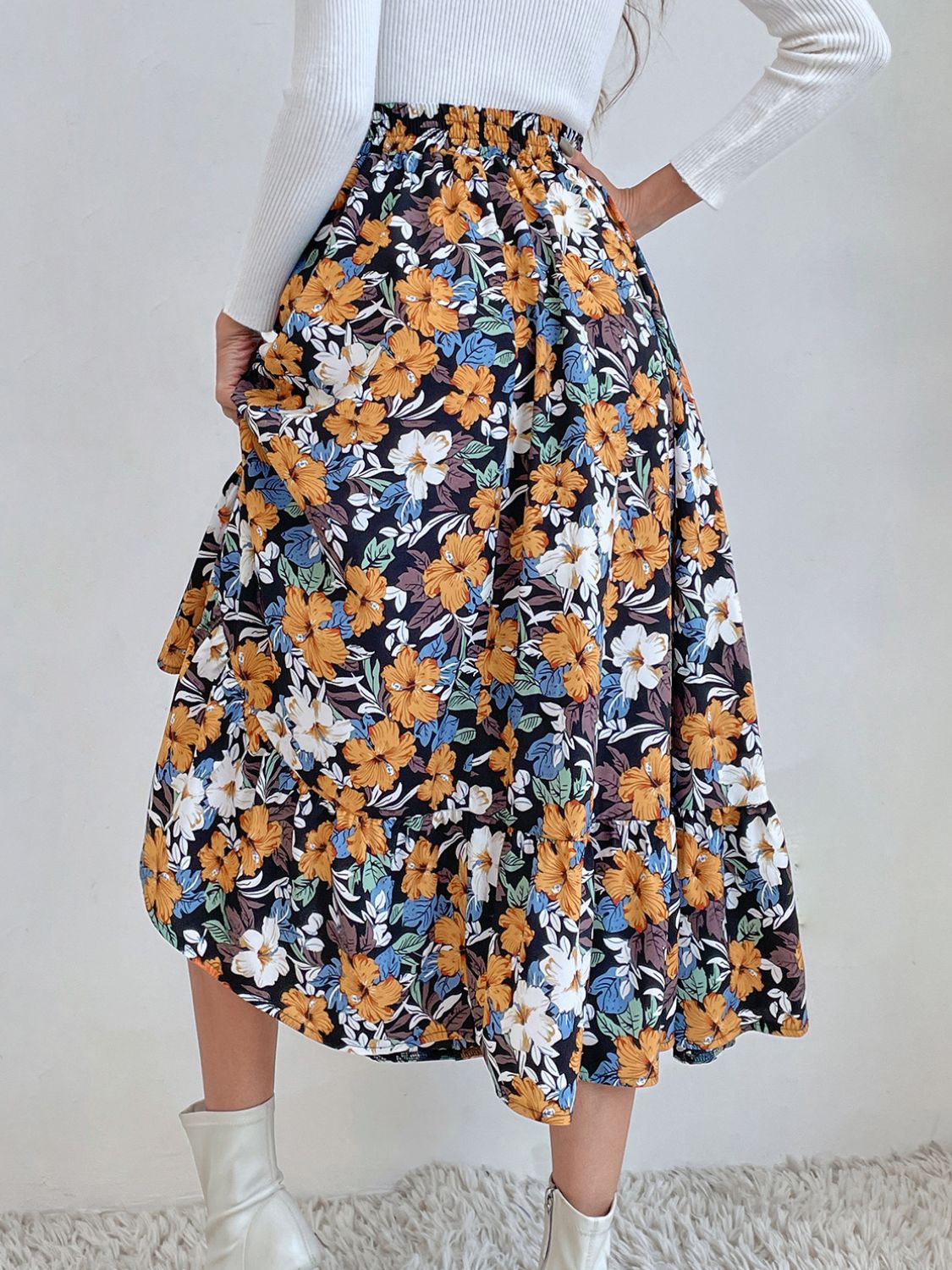 Tiered midi skirt with a black floral print, elastic waist, and flowy hem.