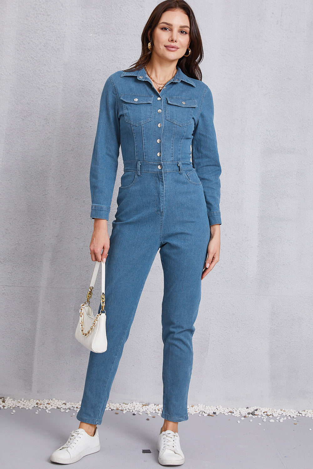 Denim utility jumpsuit in medium wash with defined waist, button front, and chest pockets.