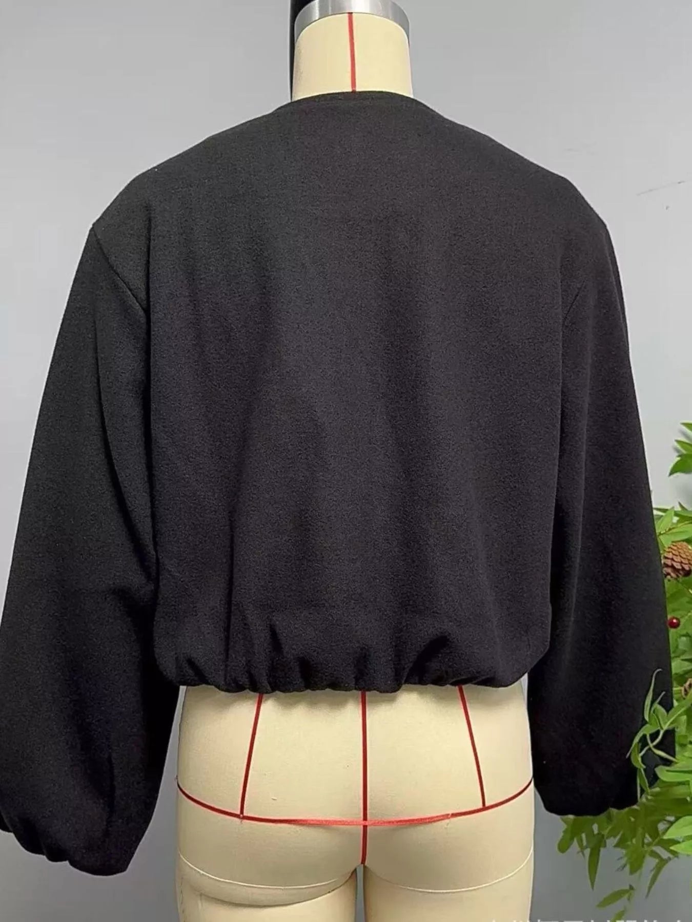 Black cropped jacket with gathered hem and balloon sleeves.