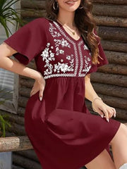 Burgundy embroidered floral v-neck mini dress with flutter sleeves and smocked waist.