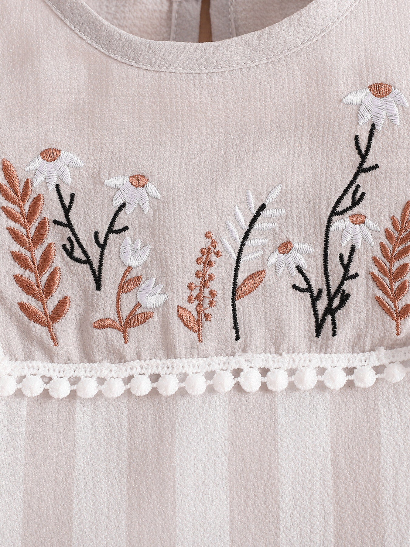 Baby two-piece set with floral embroidery and pom-pom trim.