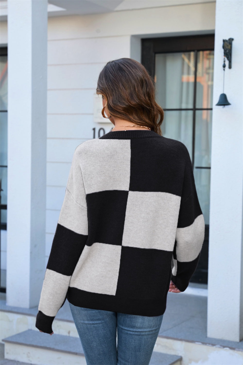 Checkerboard knit crewneck sweater in black and light grey acrylic with long sleeves.