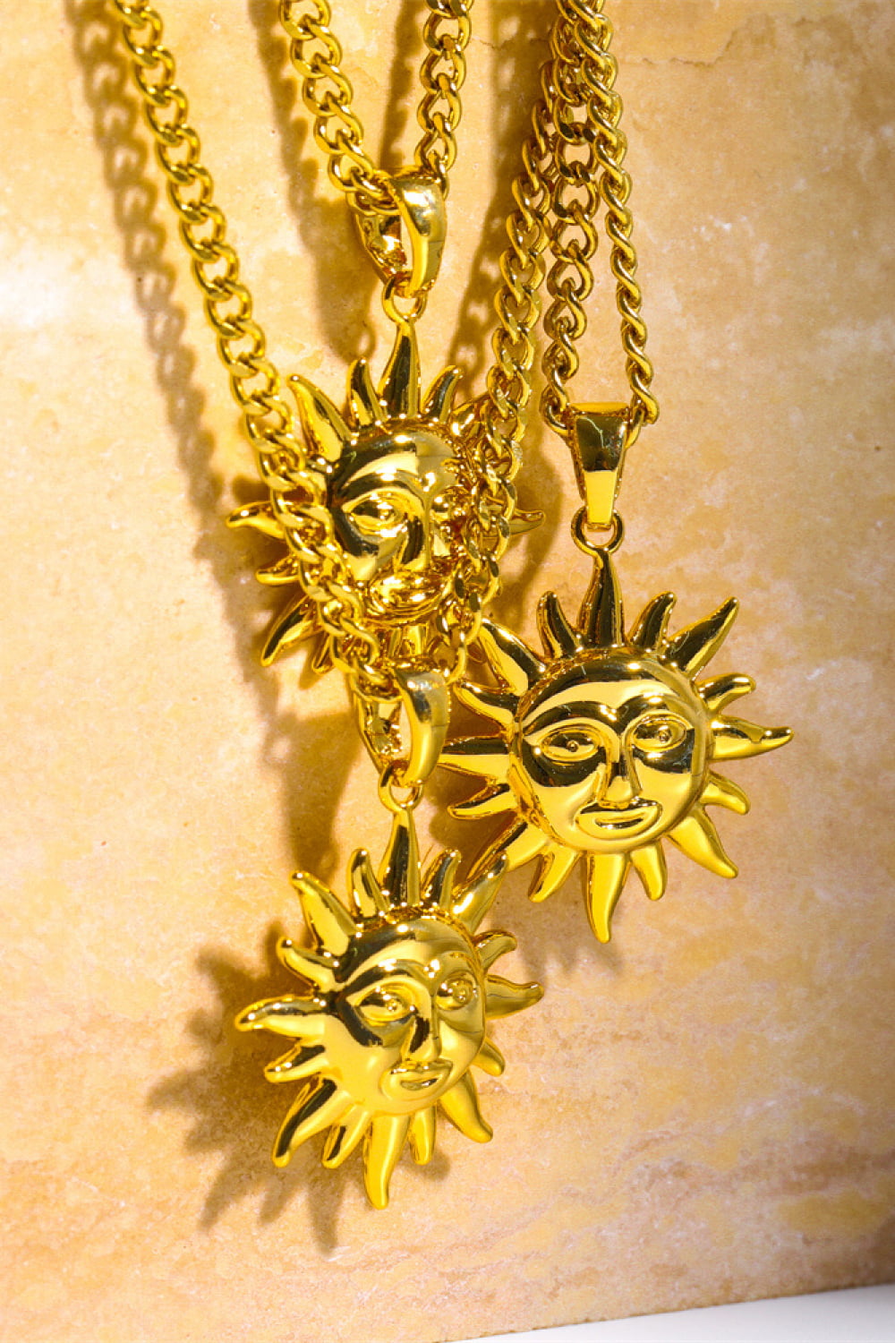Gold sunburst pendant necklaces with curb chains, featuring detailed sun face charms.