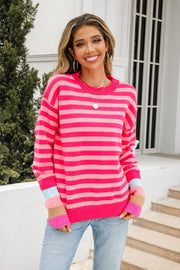 Fuchsia striped acrylic sweater with colorblock cuffs, crew neck, and long sleeves.