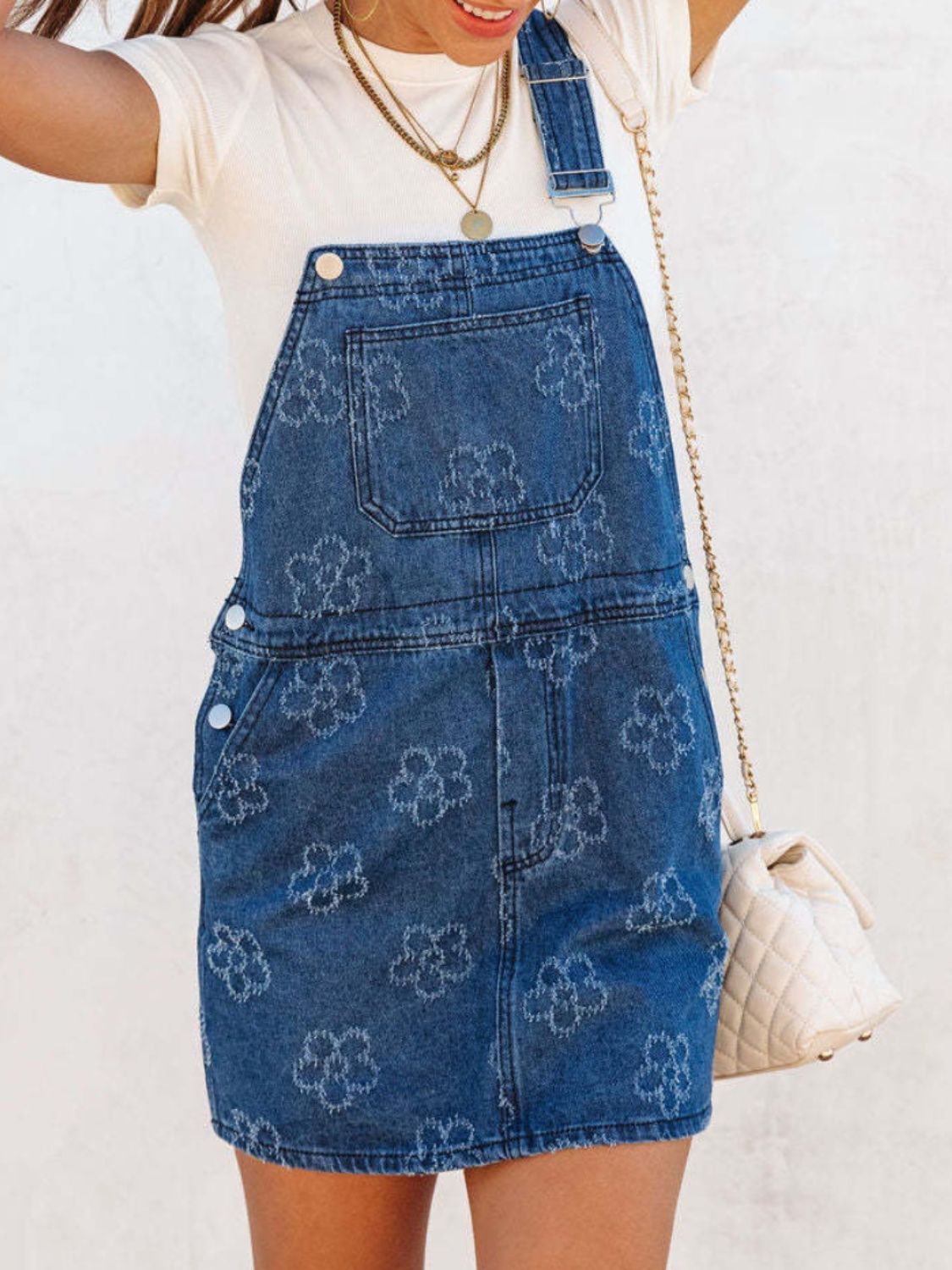 Embroidered denim pinafore dress in peacock blue with a floral pattern.