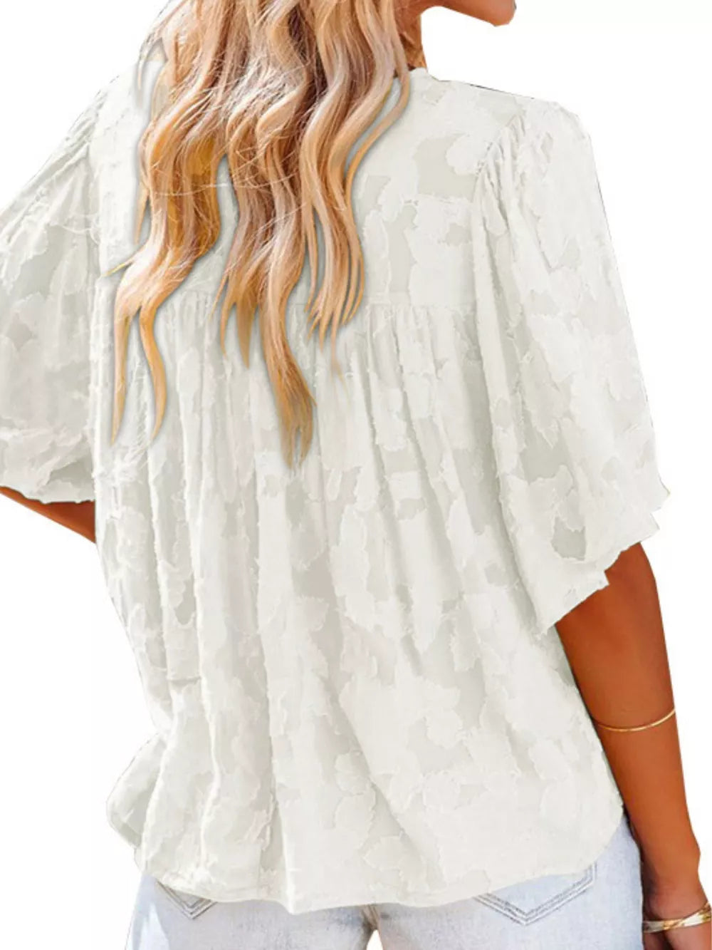 White textured V-neck blouse with ruffled detail and short sleeves.