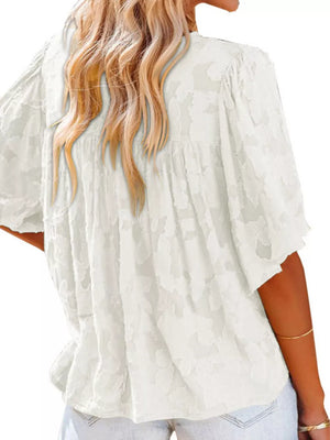 White textured V-neck blouse with ruffled detail and short sleeves.