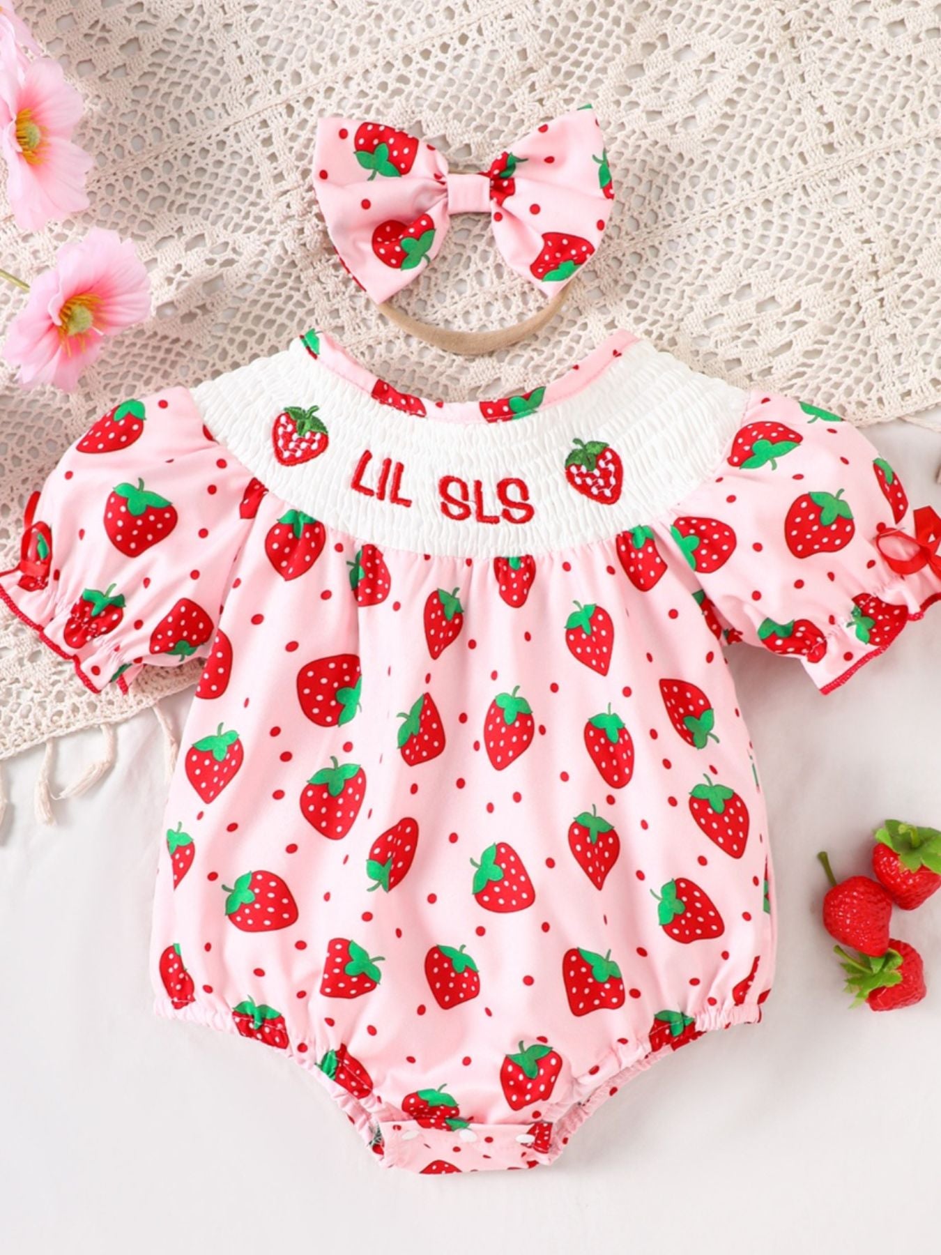Baby pink cotton smocked one-piece with strawberry print and bow headband.