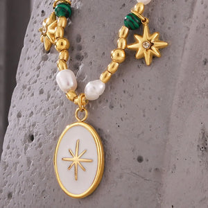 Gold necklace with pearls, green beads, starburst charms and oval pendant.