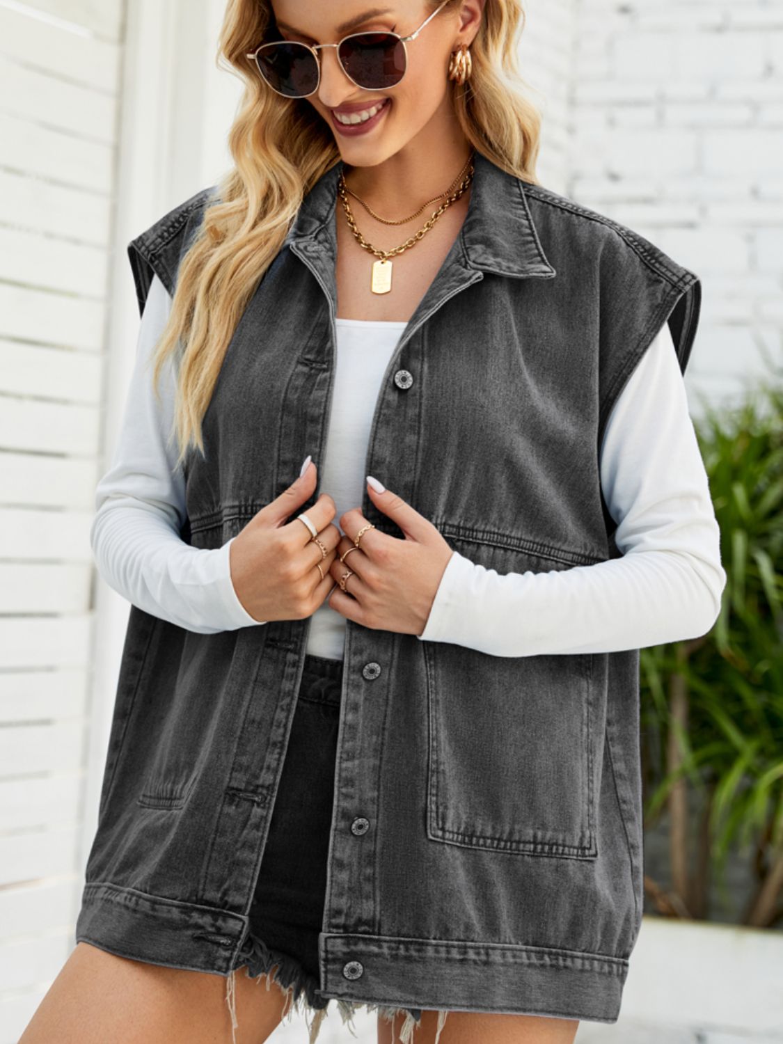 Dark denim utility vest with oversized pockets, collared neck, button front, and raw hem.
