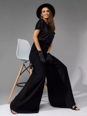 Black wide-leg jumpsuit with shimmering sequin top and tie detail.