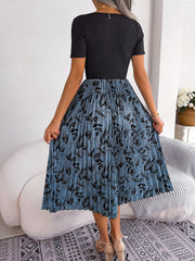 Botanical pleated midi dress in blue with black floral print and short sleeves.