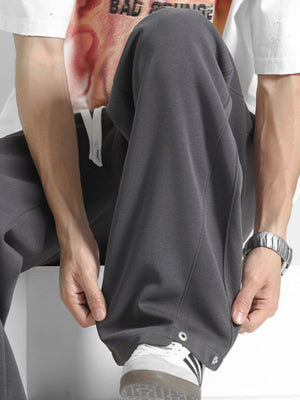 Men's dark gray drawstring sweatpants with snap details at the ankle.