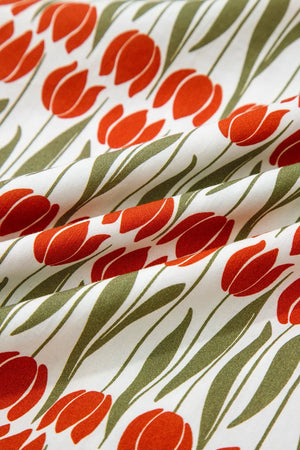 Cotton mini dress with vibrant red tulip print and green stems on white fabric.