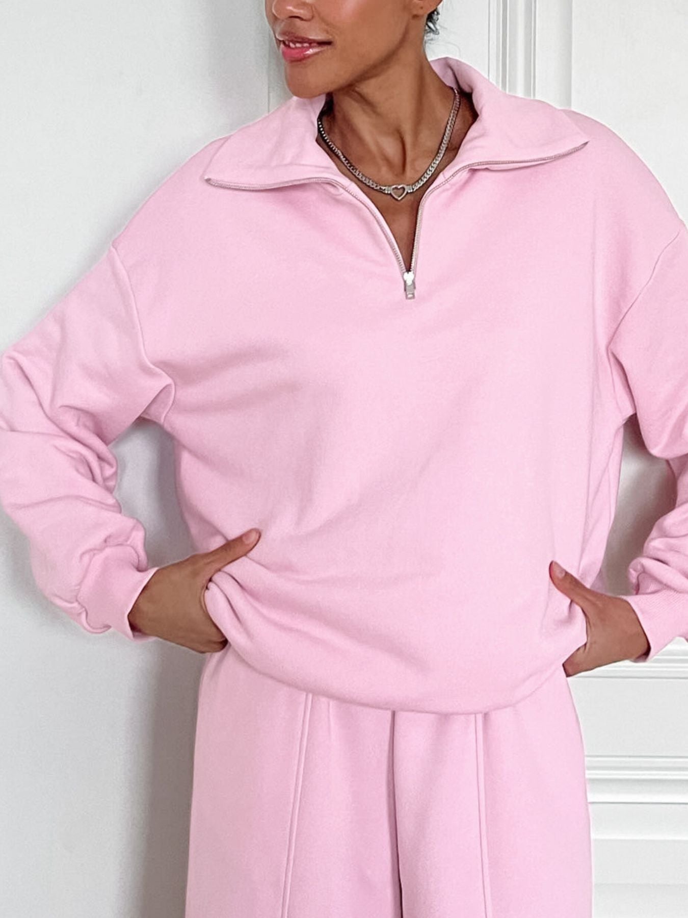 Blush pink quarter zip collared long sleeve top and pants set with silver zipper detail.