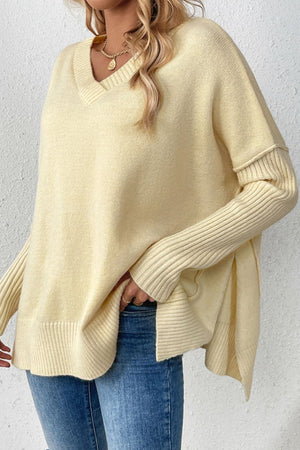 Light yellow V-neck knit sweater with asymmetric hemline and ribbed sleeves.