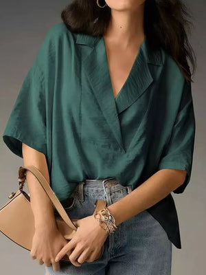 Dark green V-neck half sleeve shirt with a relaxed fit, styled with jeans and a handbag.