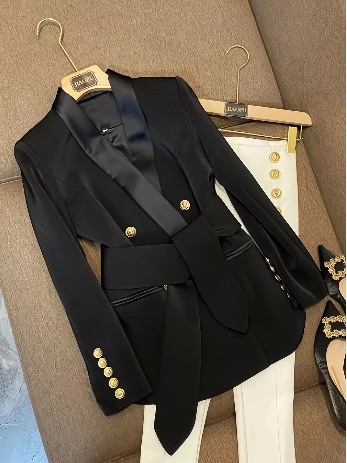 Black double-breasted tailored blazer with satin lapels, gold buttons, and a matching belt.