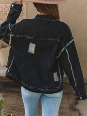 Black denim trucker jacket with raw hem, distressed details, and button closure.