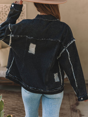 Black denim trucker jacket with raw hem, distressed details, and button closure.
