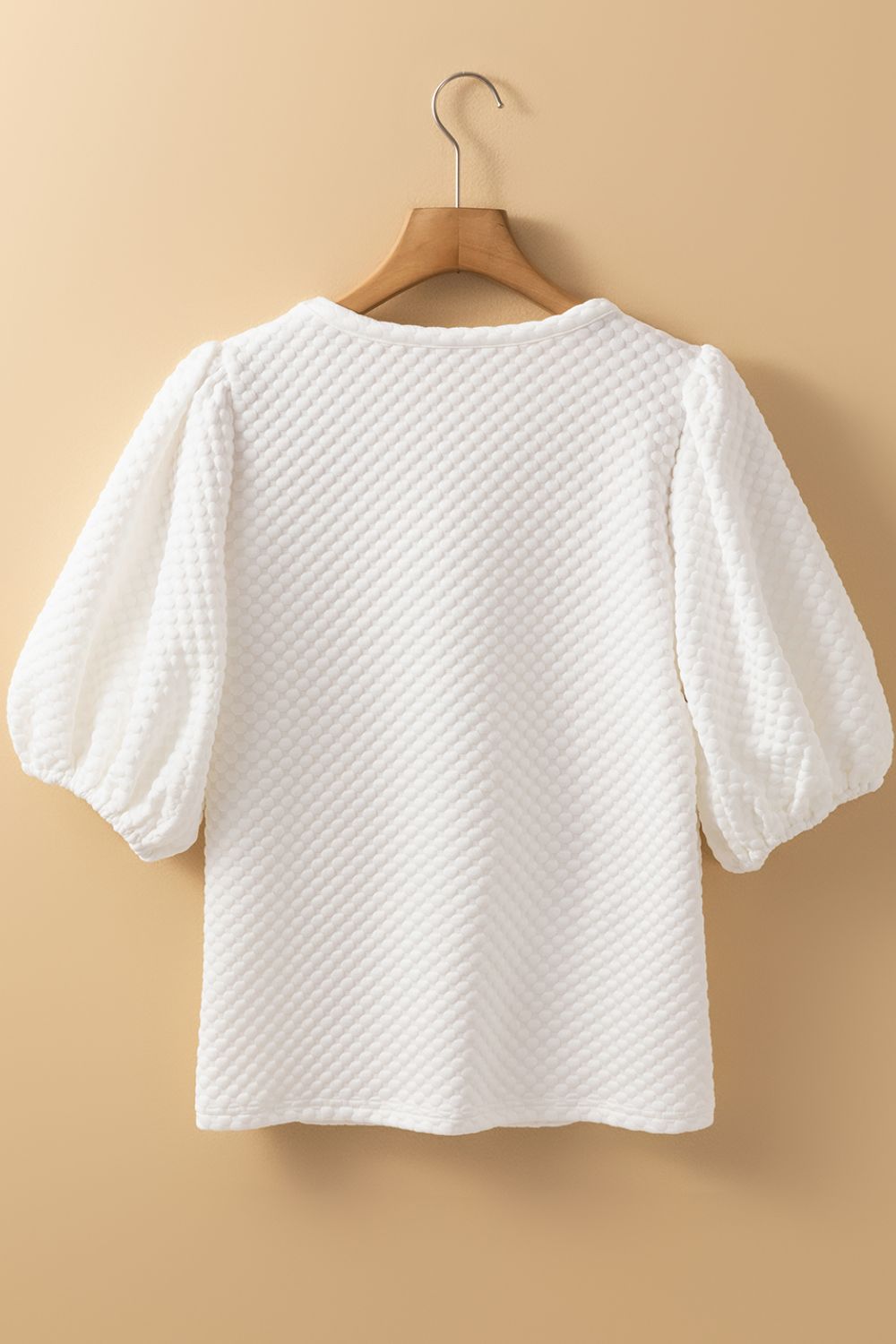 White textured quilted blouse with puff sleeves and a round neckline.
