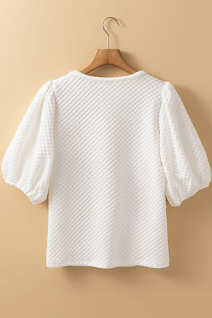 White textured quilted blouse with puff sleeves and a round neckline.